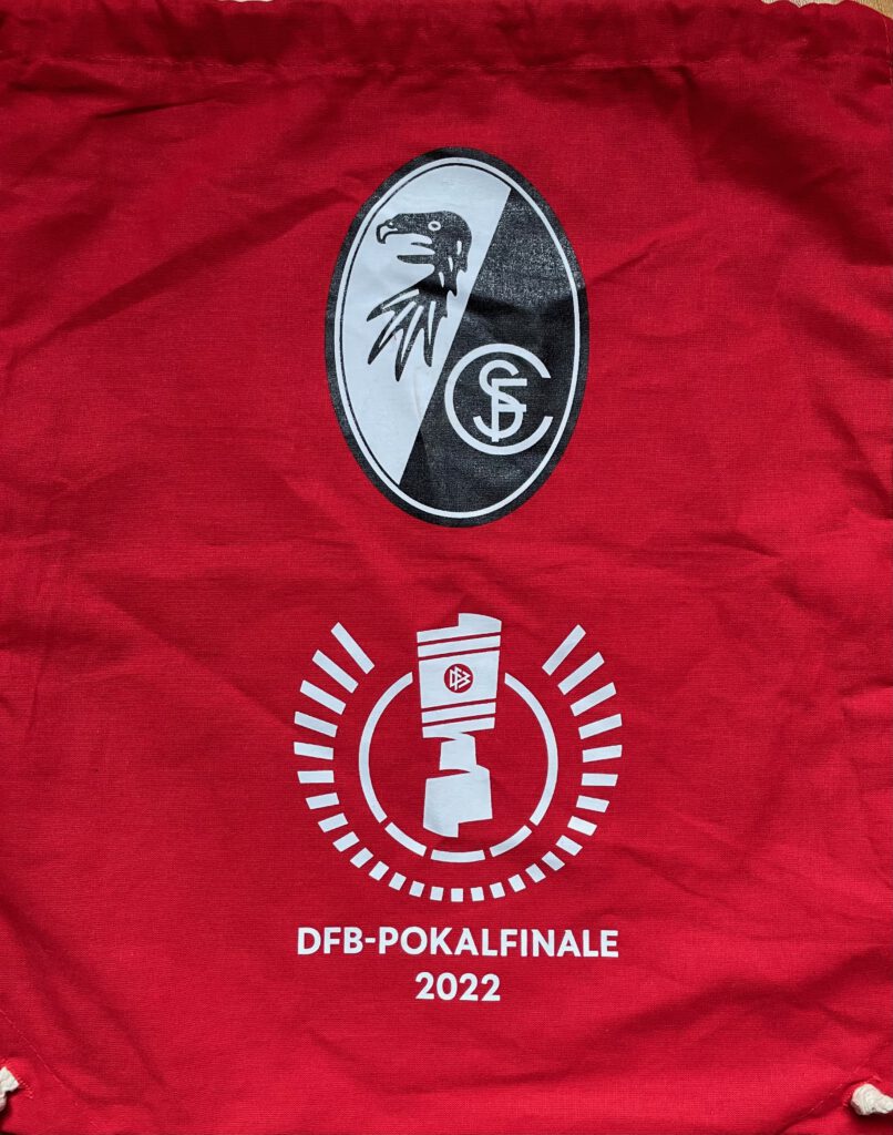 Das Foto zeigt einen roten Stoffbeutel mit dem Logo des SC Freiburg